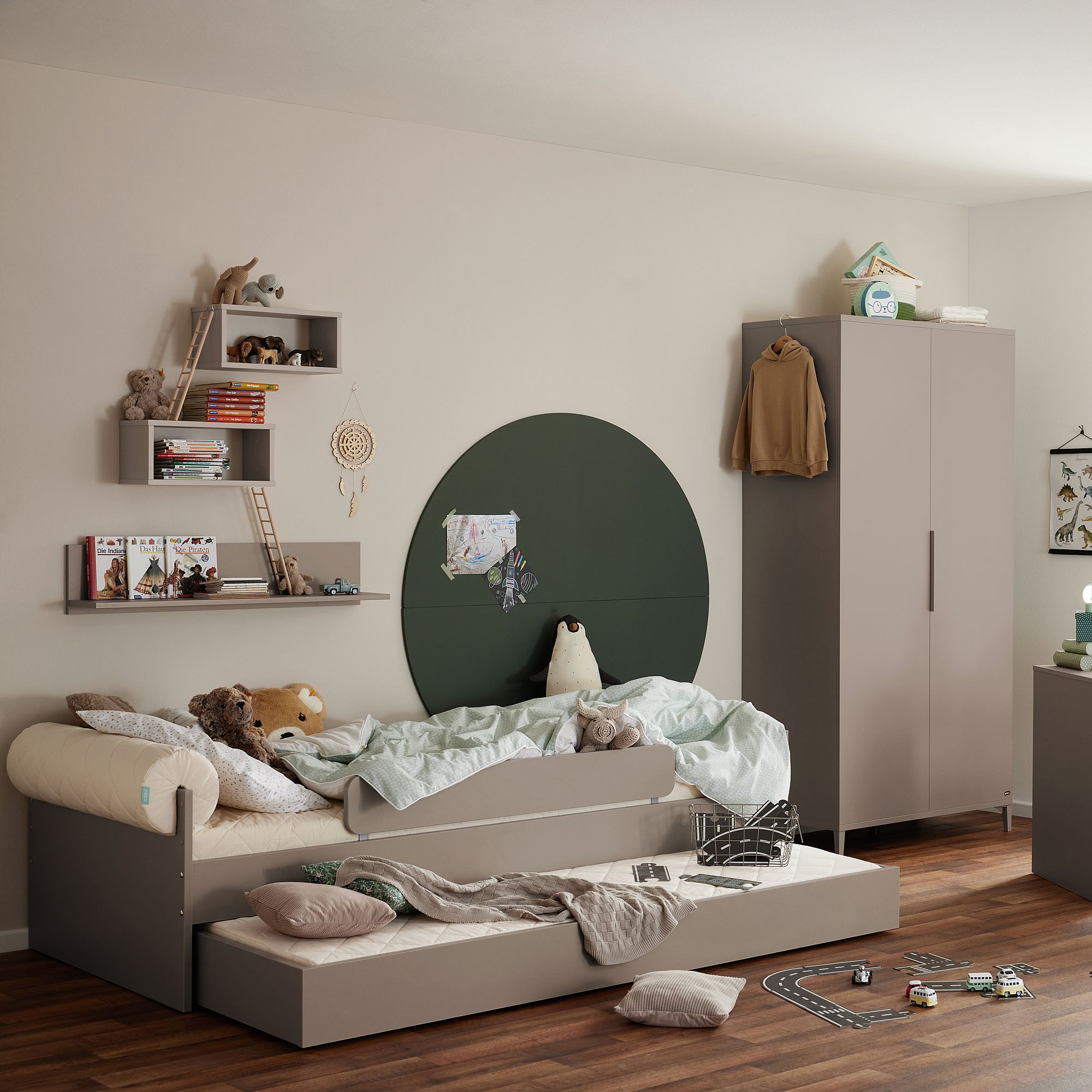 Kinderzimmer mit ausziehbarem Bett, Spielzeug und weicher, neutraler Einrichtung.