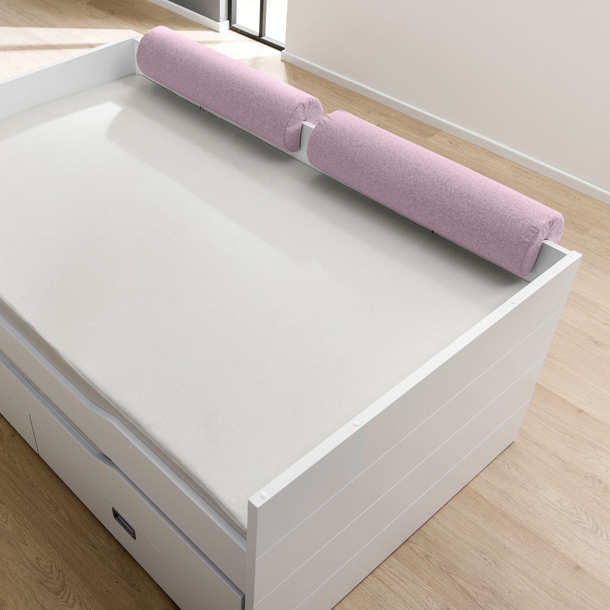 Comfort-Rolle 85,30 x Ø 20 cm, Mikrofaser Dunkelrosa Ein weißes Bett mit zwei rosafarbenen zylindrischen Kissen darauf, neben einem sonnendurchfluteten Fenster.