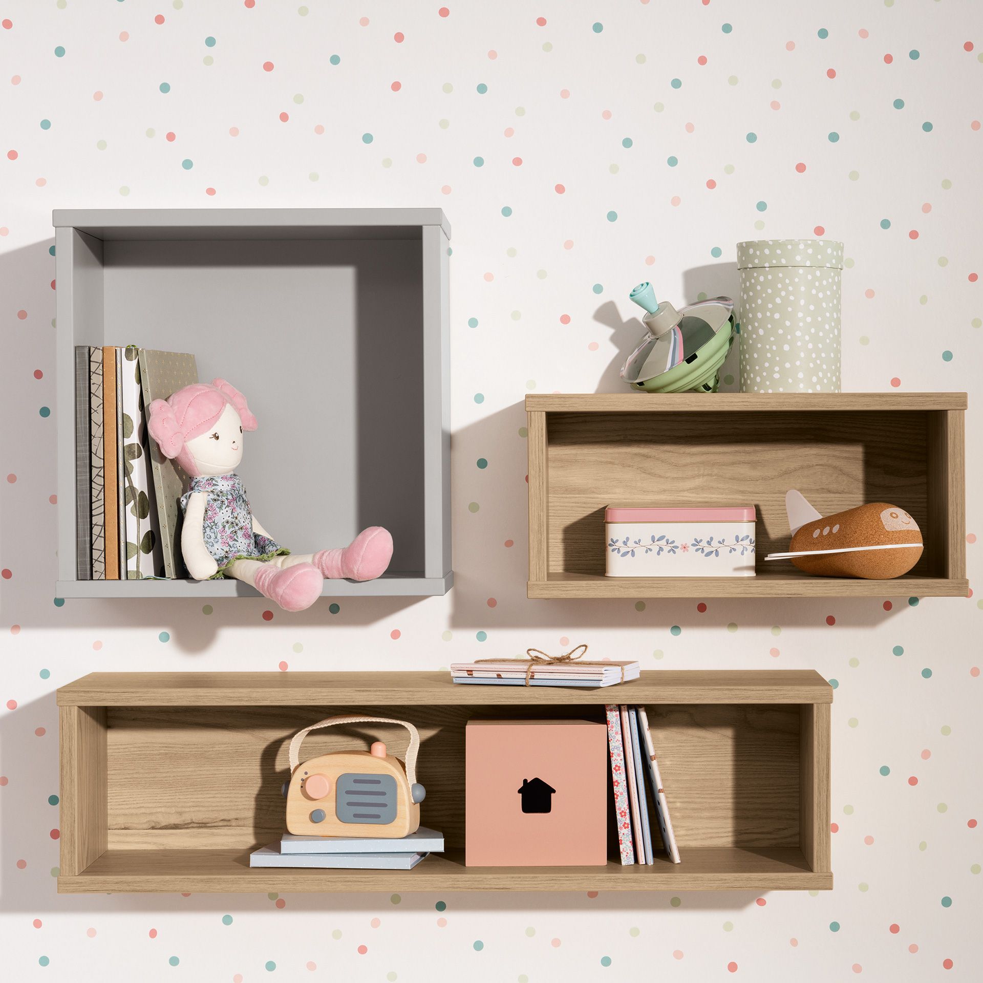 Drei Wandregale mit Spielzeug, Büchern und Dekoration vor einer gepunkteten Wand.
