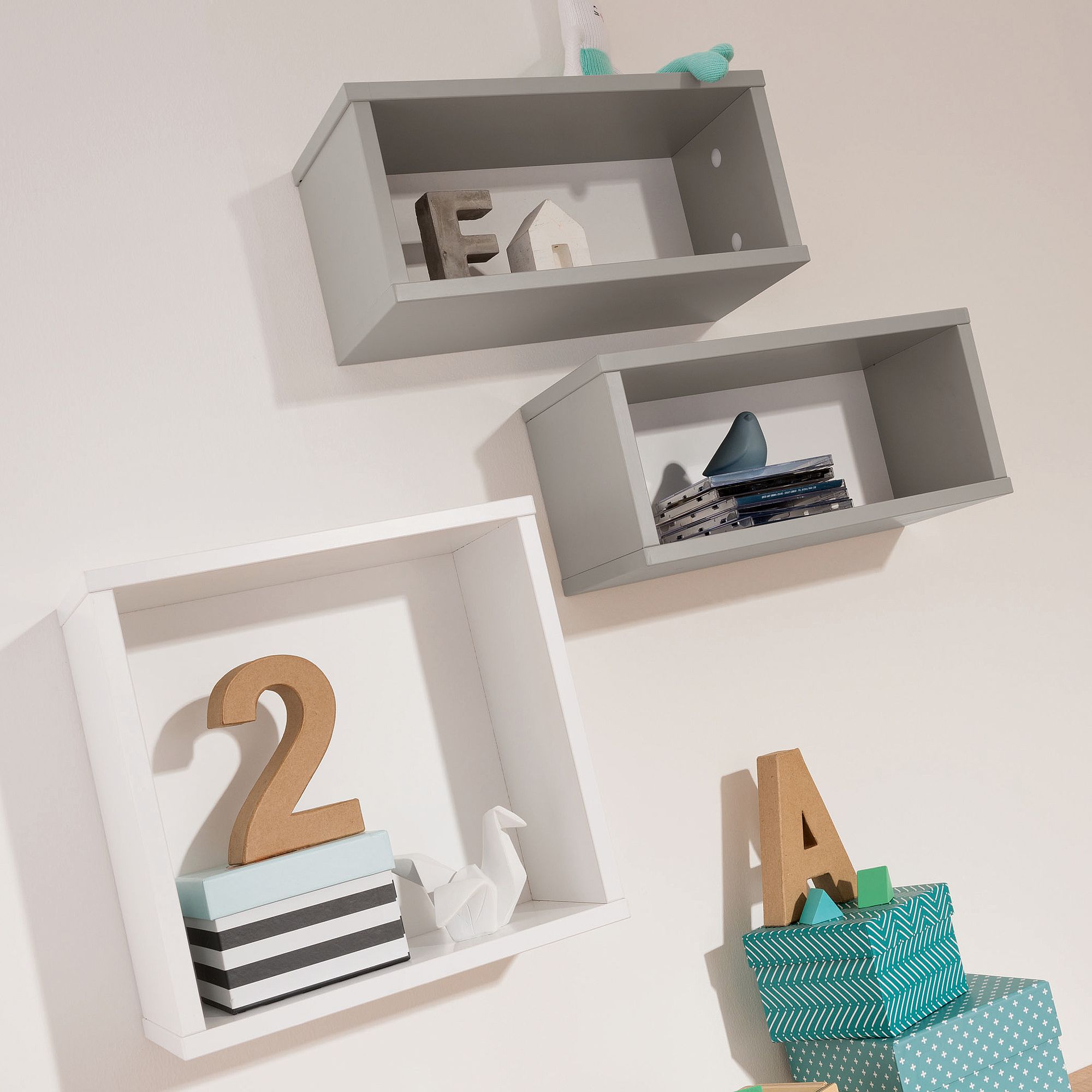 Drei Wandregale mit Dekoration: Briefe, Schachteln, Bücher und ein Origami-Kranich aus Papier.