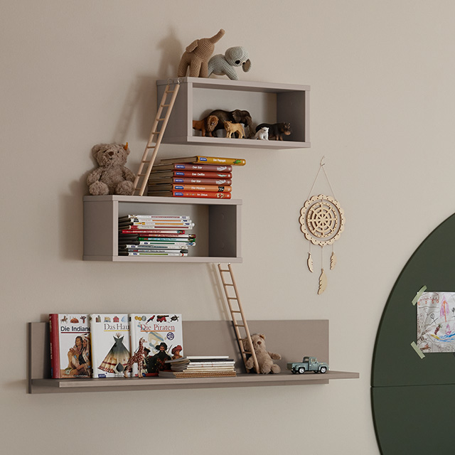 Wandregale mit Büchern, Spielzeugtieren und kleinen Leitern; Traumfänger und Spielzeugauto stehen ebenfalls vor einer hellen Wand.