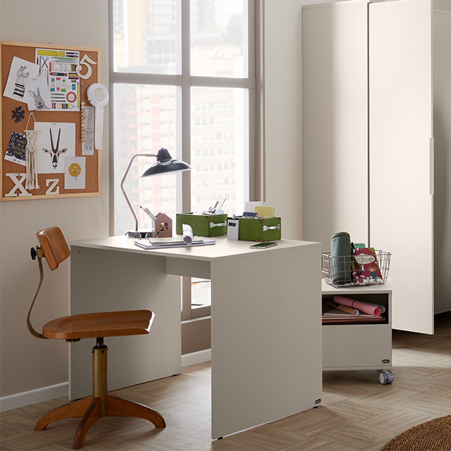 Minimalistisches Heimbüro mit Holzstuhl, weißem Schreibtisch, Korkplatte und großem Fenster mit Blick auf die Gebäude der Stadt.