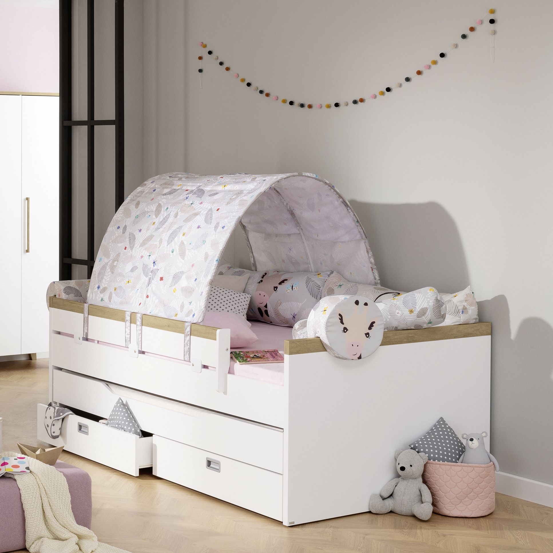 Kinderbett mit Baldachin, Tierkissen, Kuscheltieren und Schubladen.
