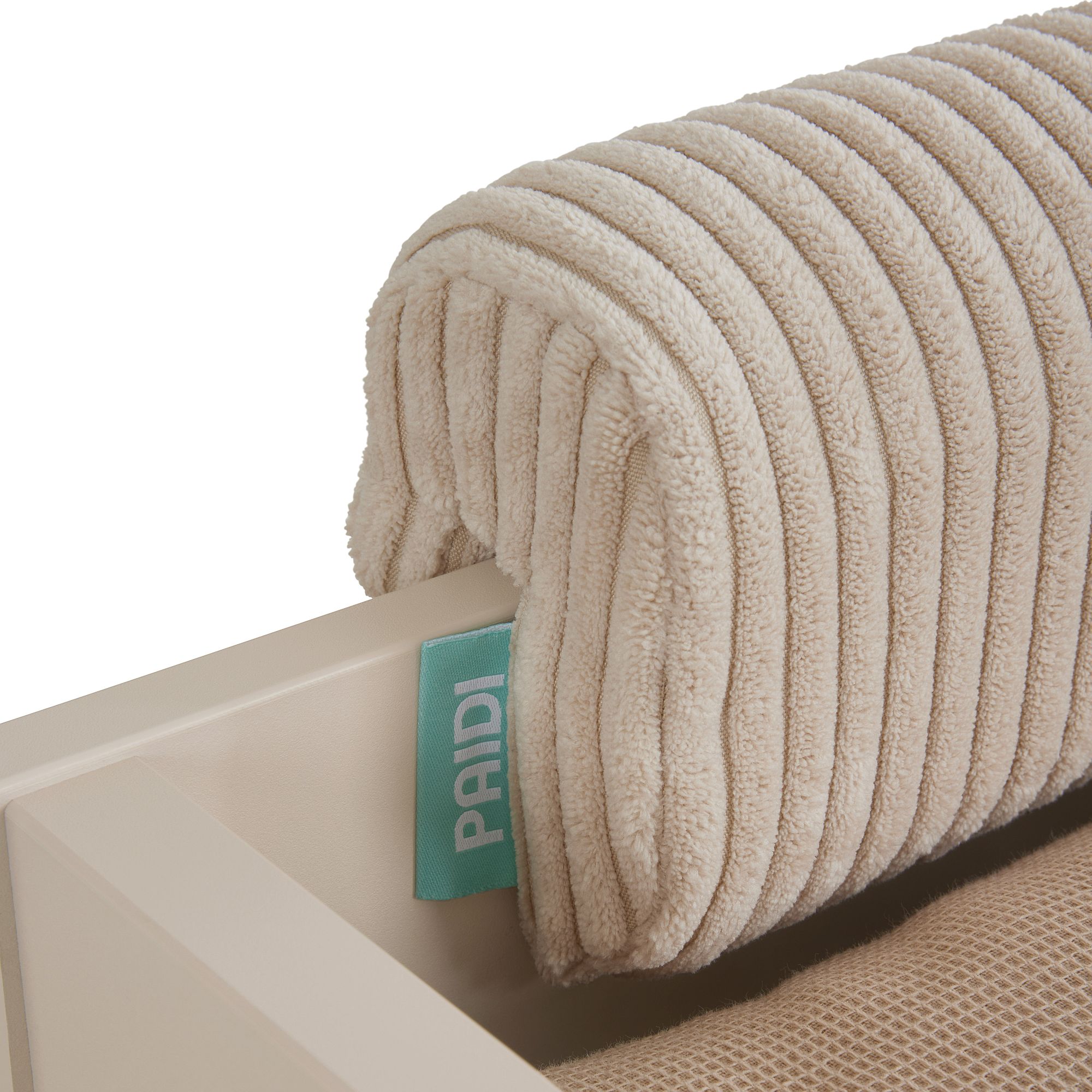 Beigefarbenes, geripptes Kissen mit einem blauen PAIDI-Anhänger auf einer hellen Oberfläche.