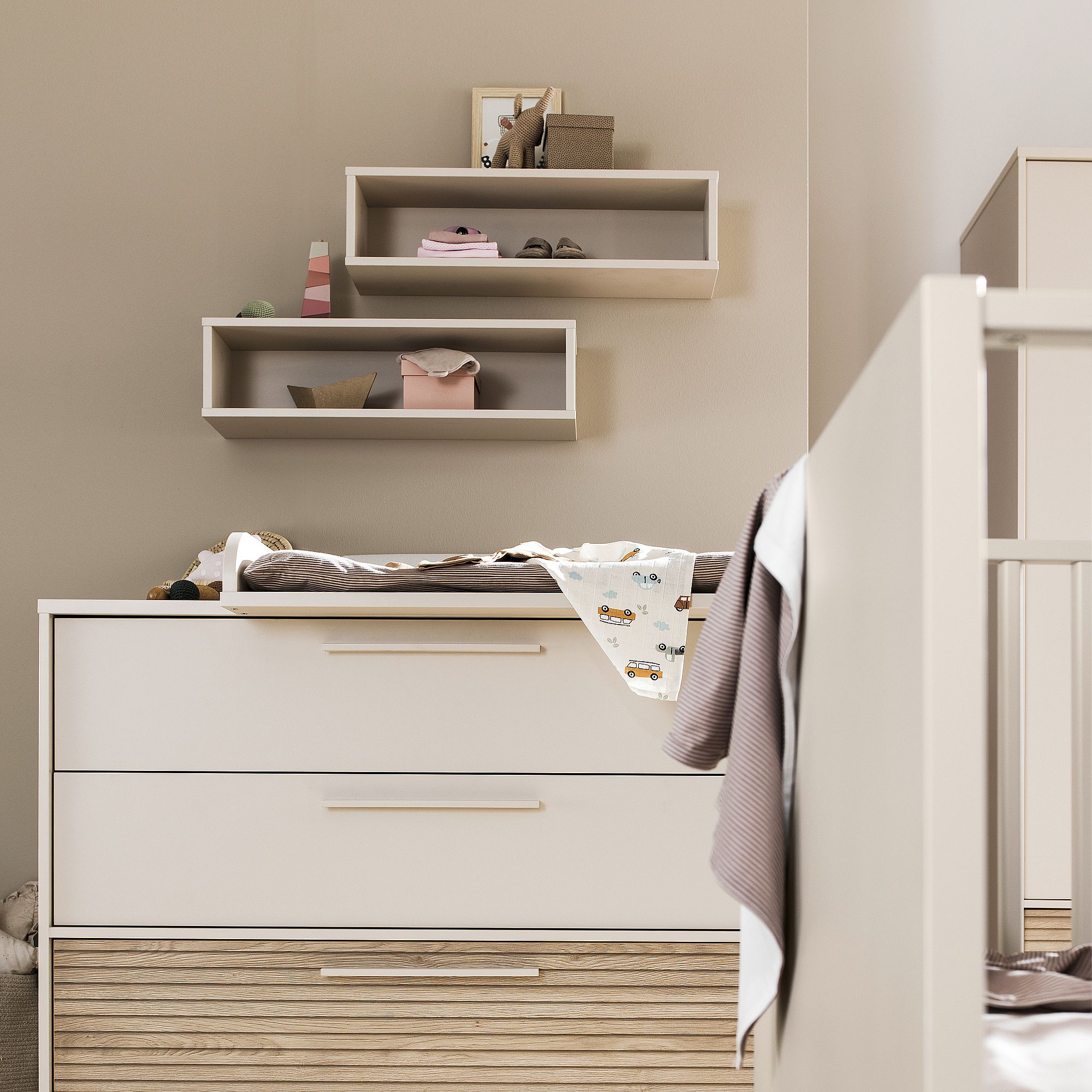 Modernes Baby-Kinderzimmer mit Regalen, Kommode und Kinderbett in neutralen Farben.
