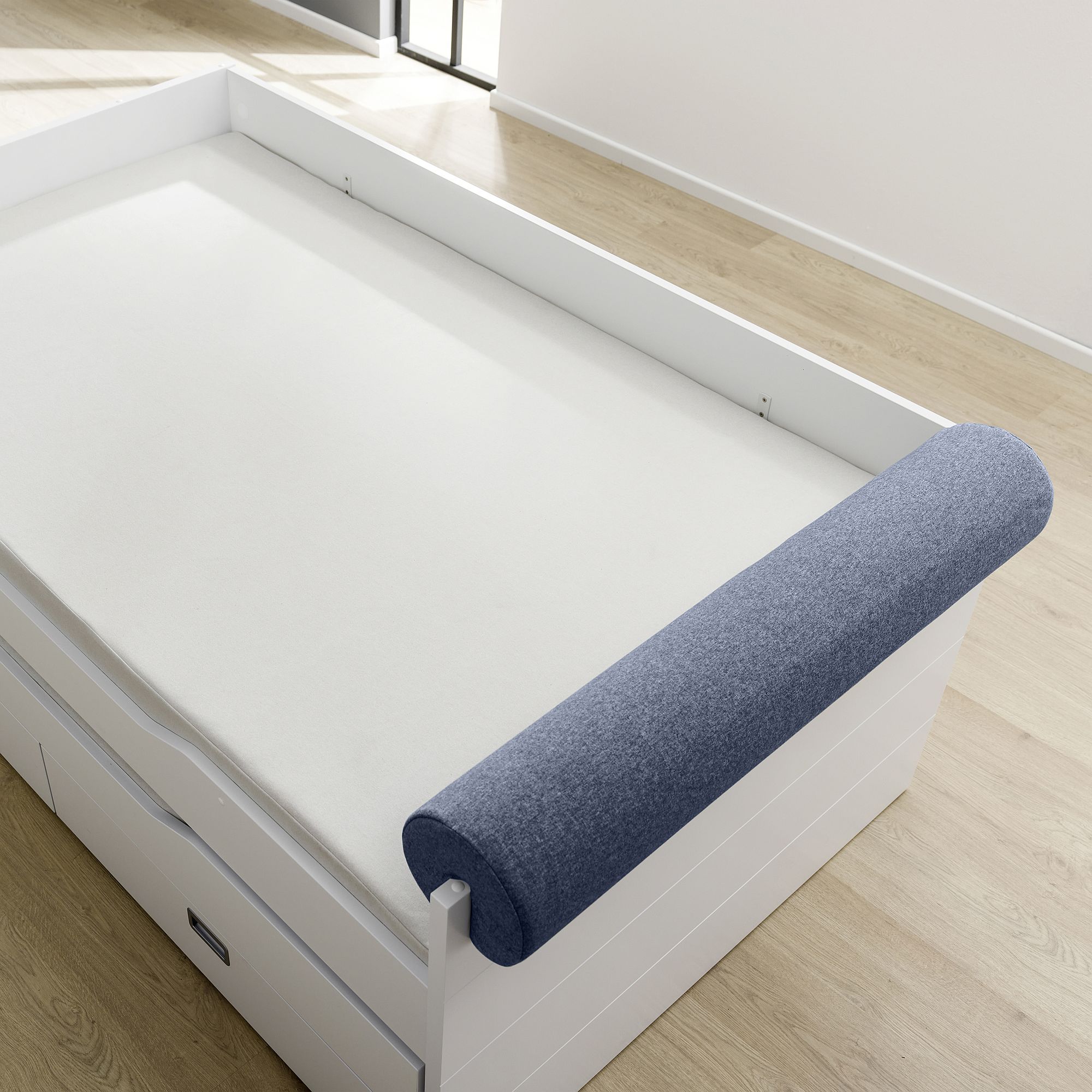 Einzelbett mit weißer Matratze und blauem, zylindrischem Bettschutz an einer Seite.