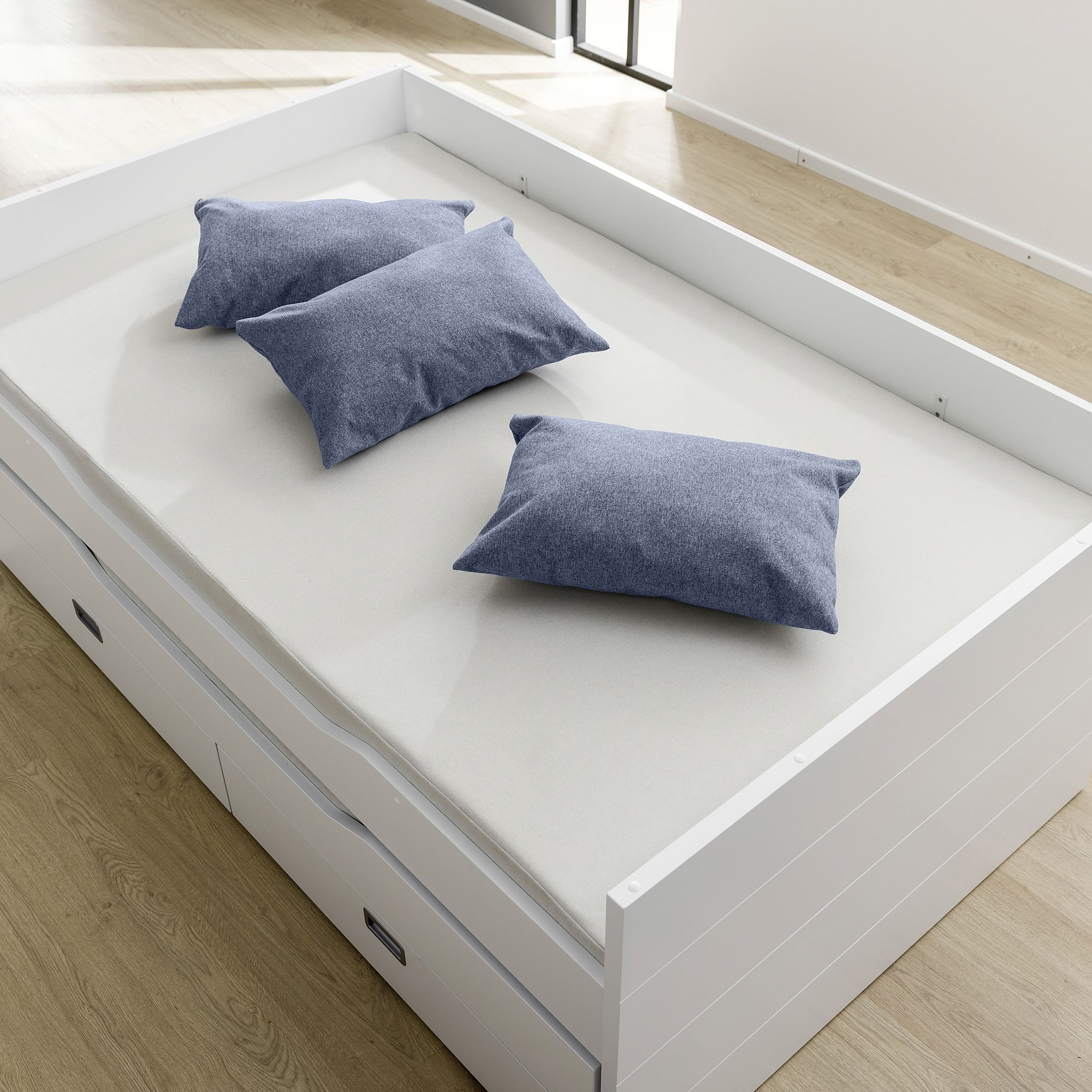 Partykissen 60 x 40 cm, Mikrofaser Tintenblau Weißes Bett mit drei blauen Kissen auf einer hellen Matratze in einem hellen Raum.