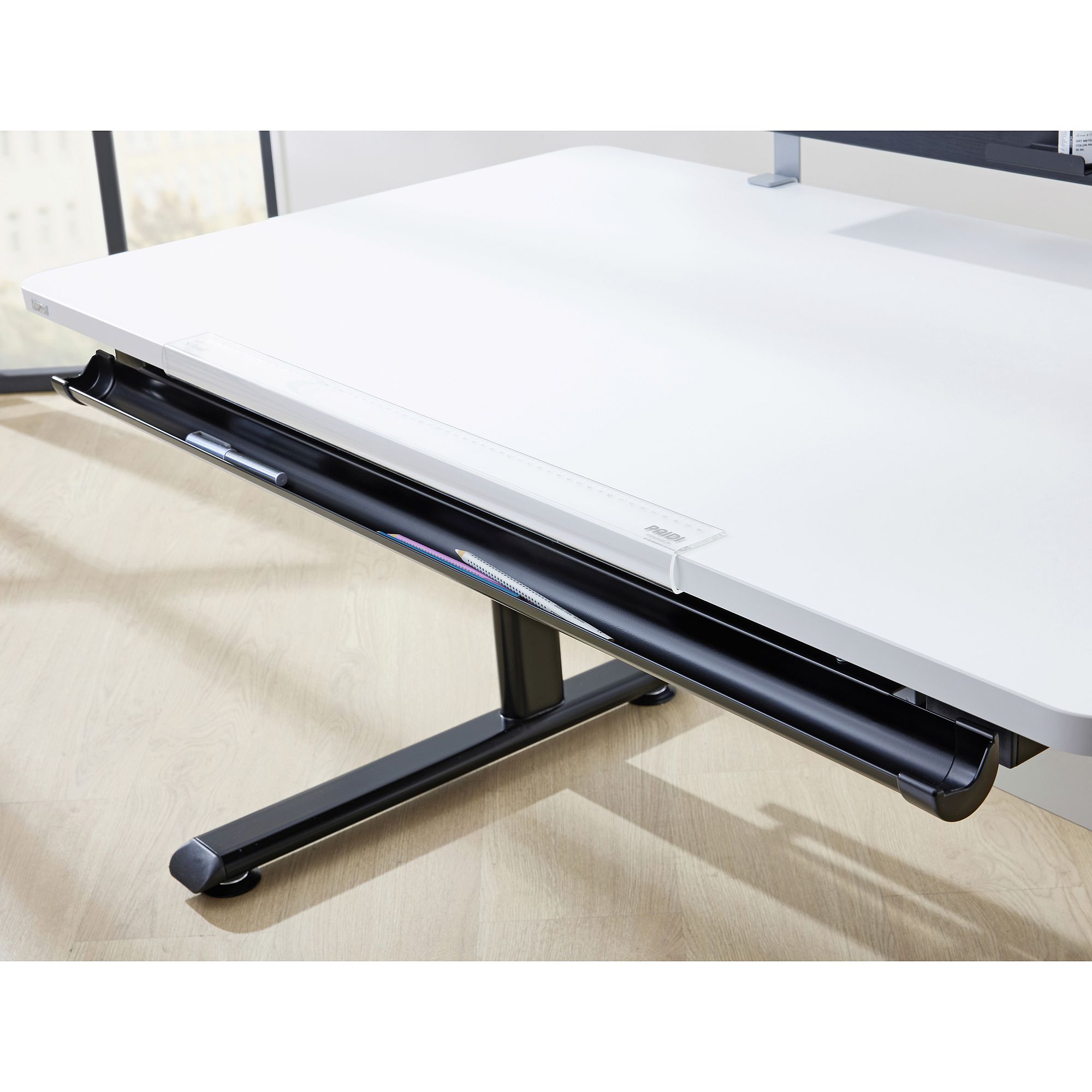 Weißer Schreibtisch mit einer schwarzen, teilweise geöffneten Schublade, in der einige Büromaterialien liegen.