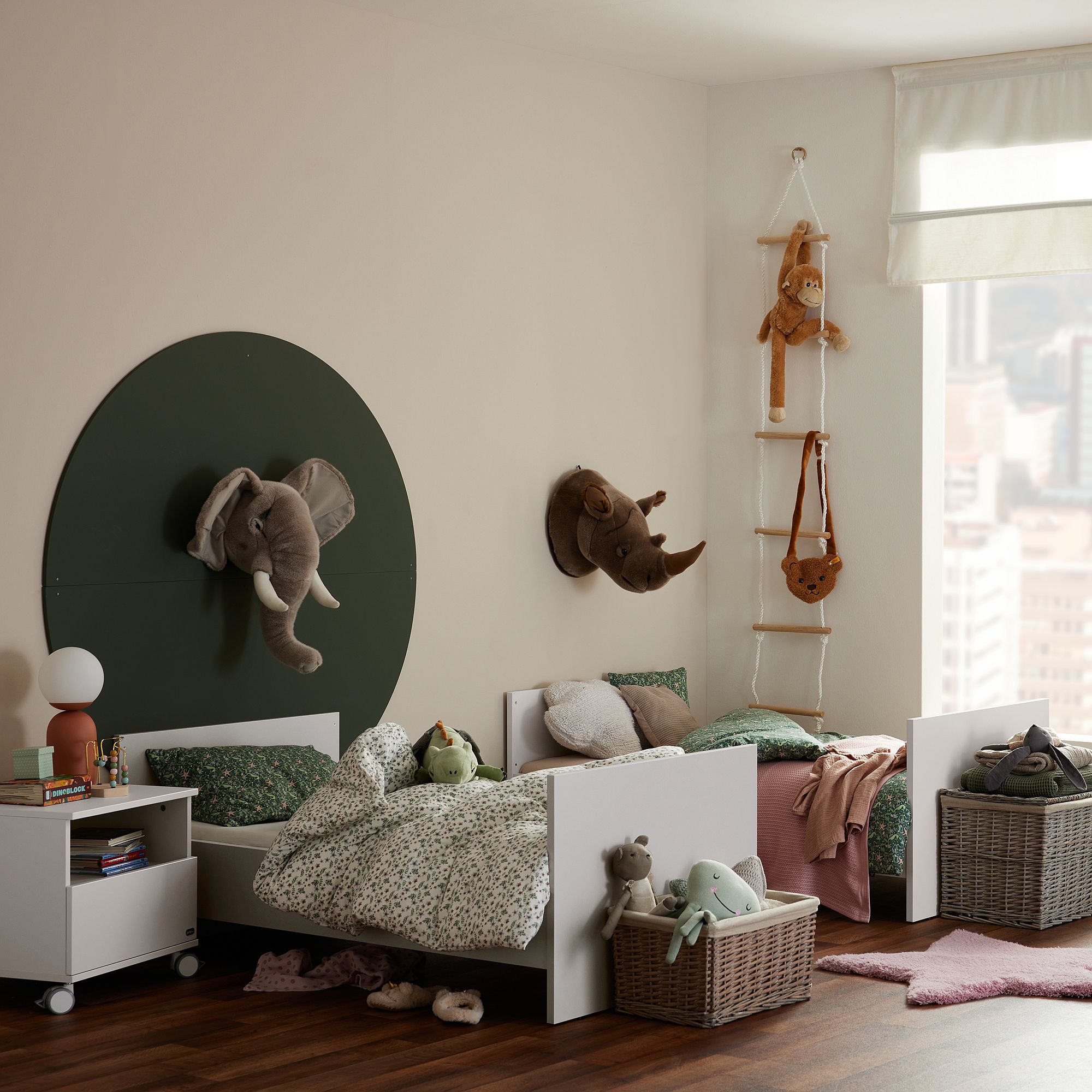 Kinderzimmer mit zwei Betten, Tierdekoration, Spielzeug und Fenster mit Stadtblick.
