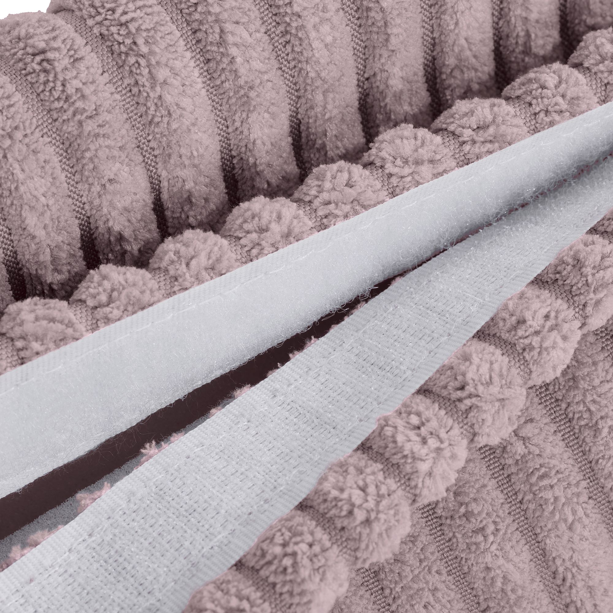 Nahaufnahme eines strukturierten, malvenfarbenen Badvorlegers mit Bommel- und Rippenmuster.