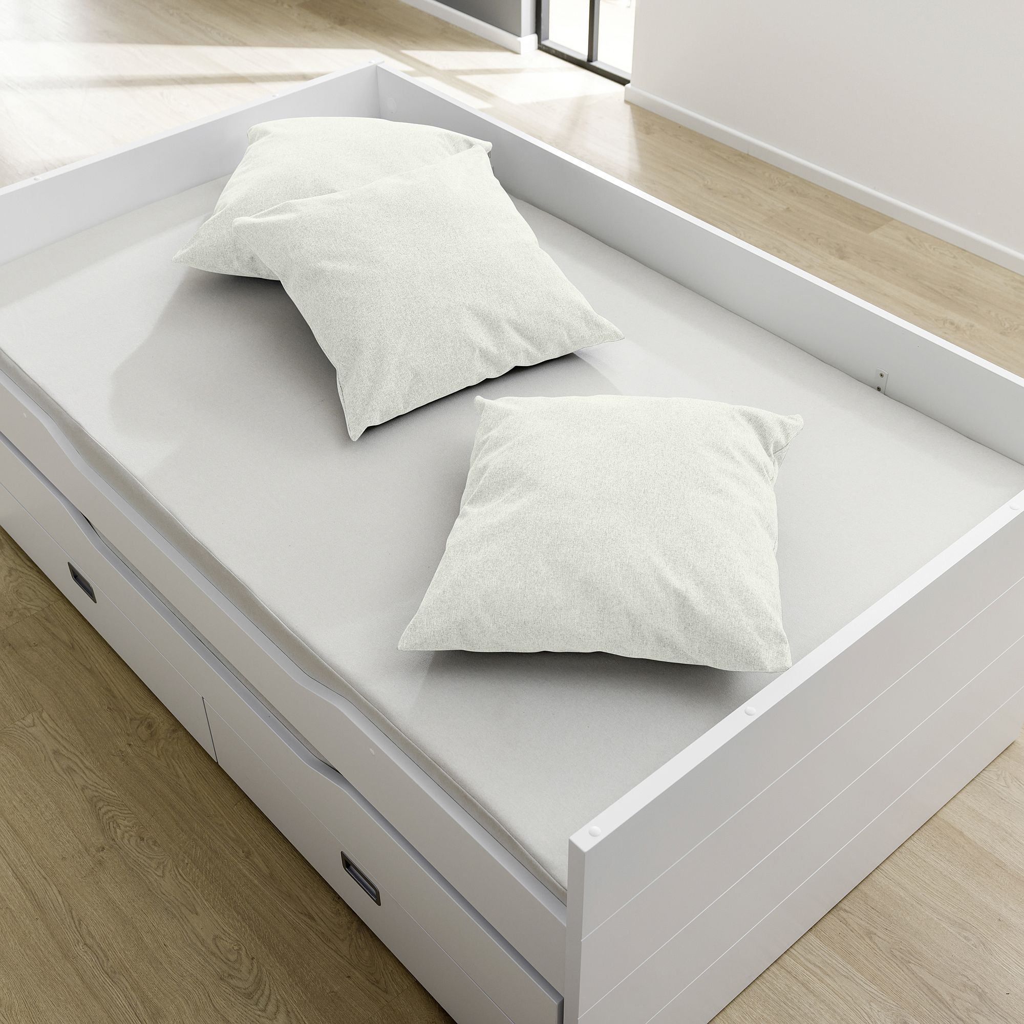 Weißes Daybed mit zwei weißen Kissen in einem hellen, modernen Raum mit Holzfußboden.