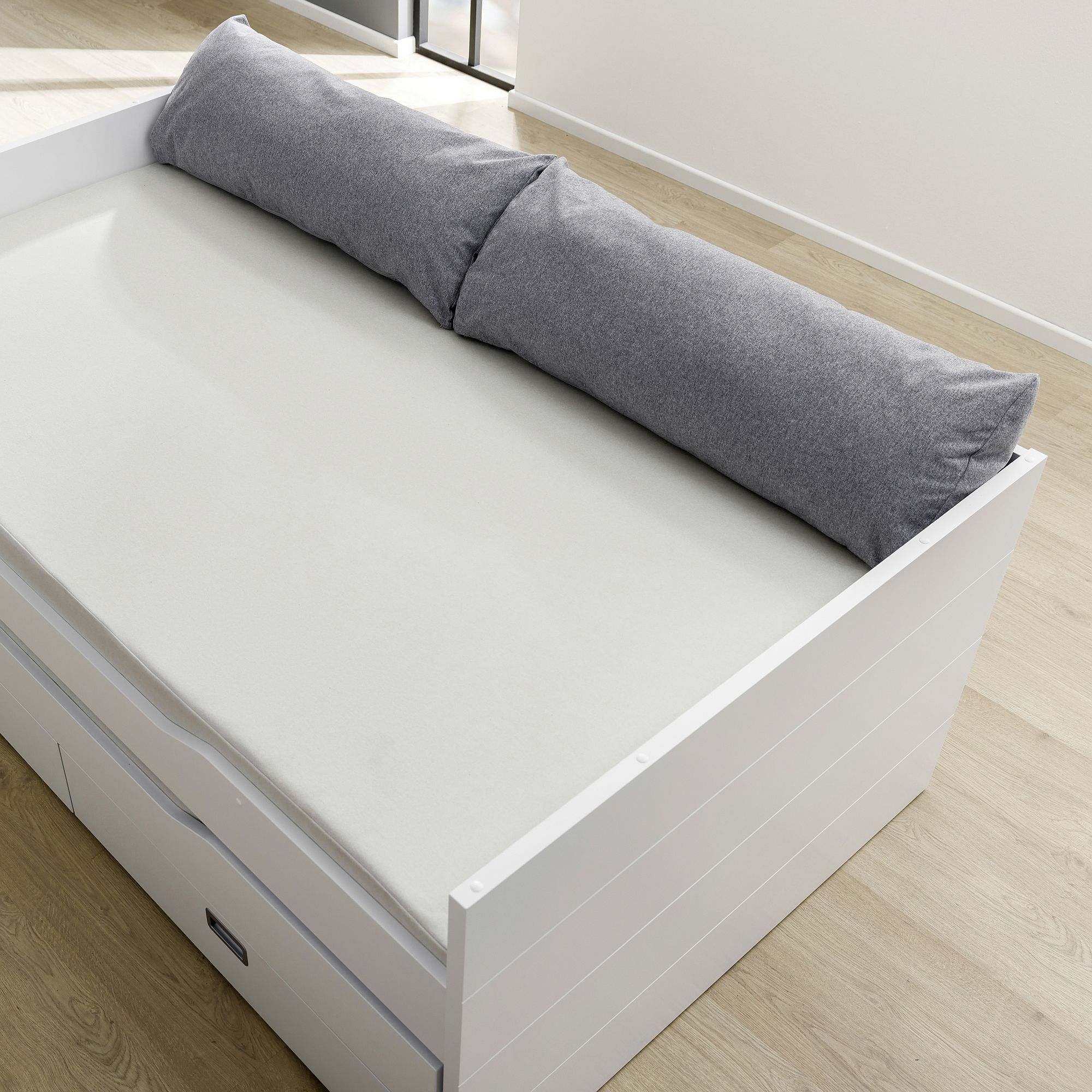 Rückenkissen 100 x 40 x 25 cm, Mikrofaser Steingrau Weißes Daybed mit leichter Matratze, grauem Rückenkissen und Schubladen auf einem Holzboden.