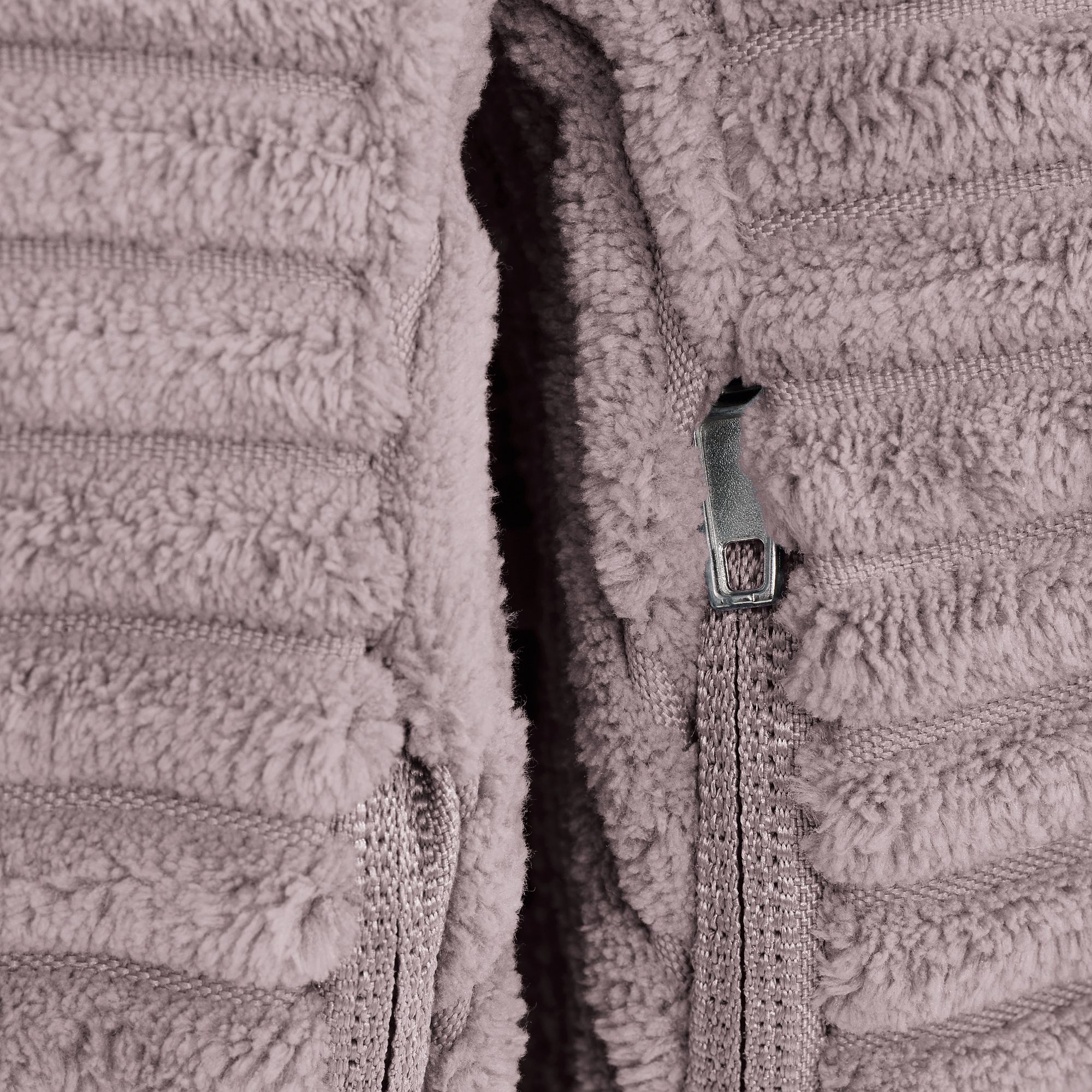 Nahaufnahme einer unscharfen lila Jacke mit teilweise geöffnetem Reißverschluss.