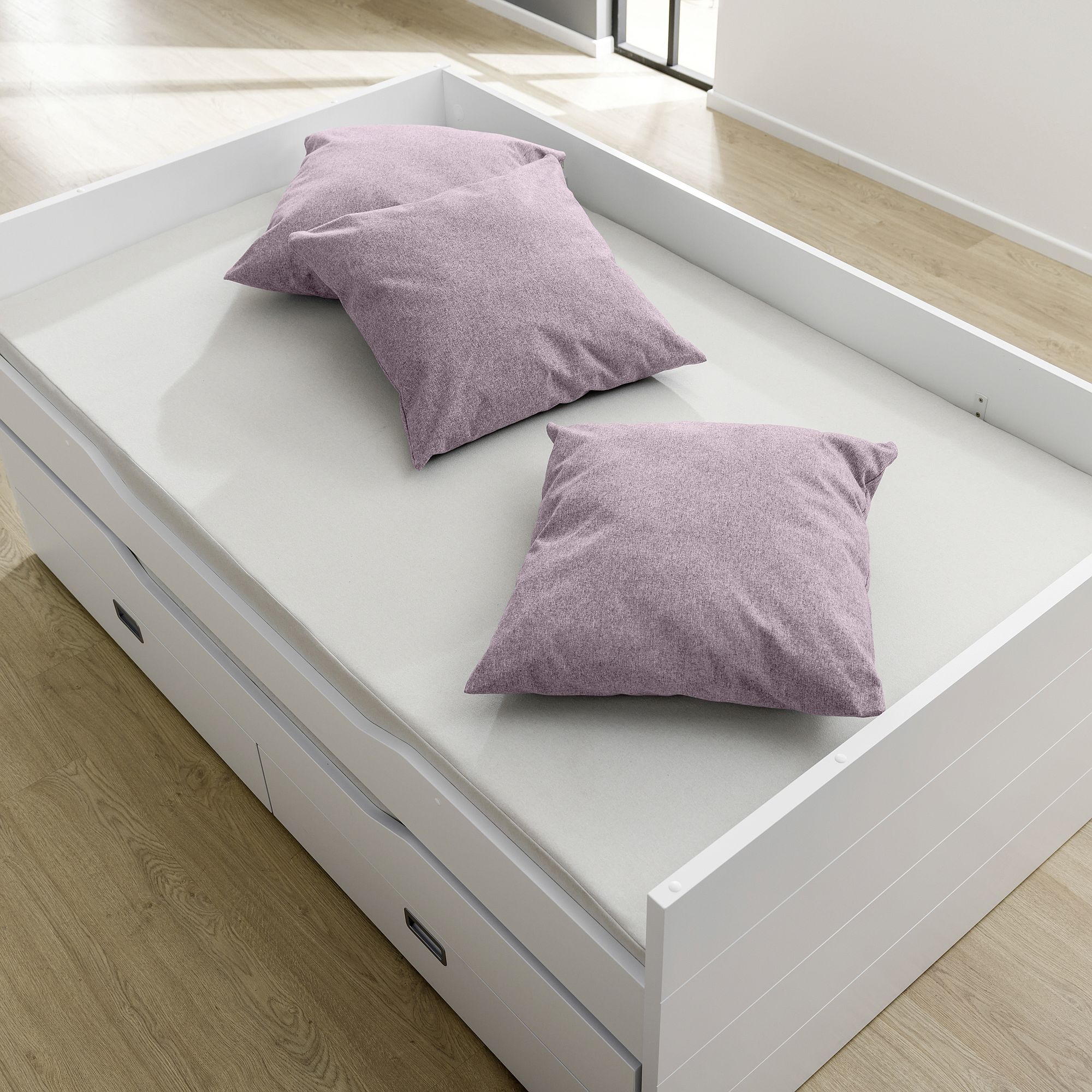 Partykissen 60 x 60 cm, Mikrofaser Dunkelrosa Ein weißes Bett mit zwei lila Kissen auf einer hellen Matratze in einem hellen Raum.