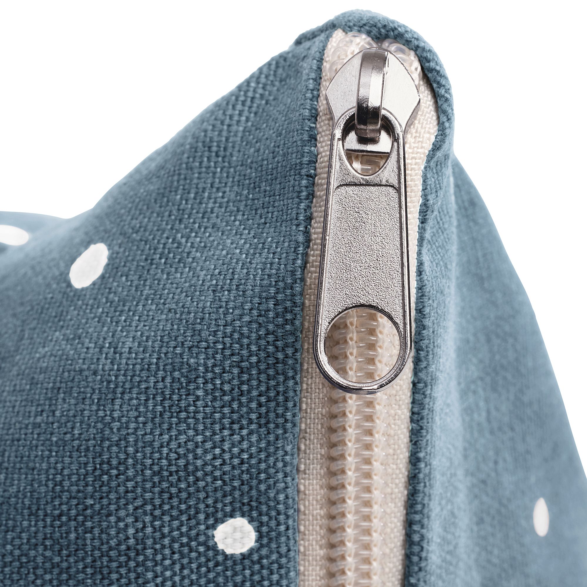 Nahaufnahme eines Metallreißverschlusses auf blauem Stoff mit weißen Tupfen.