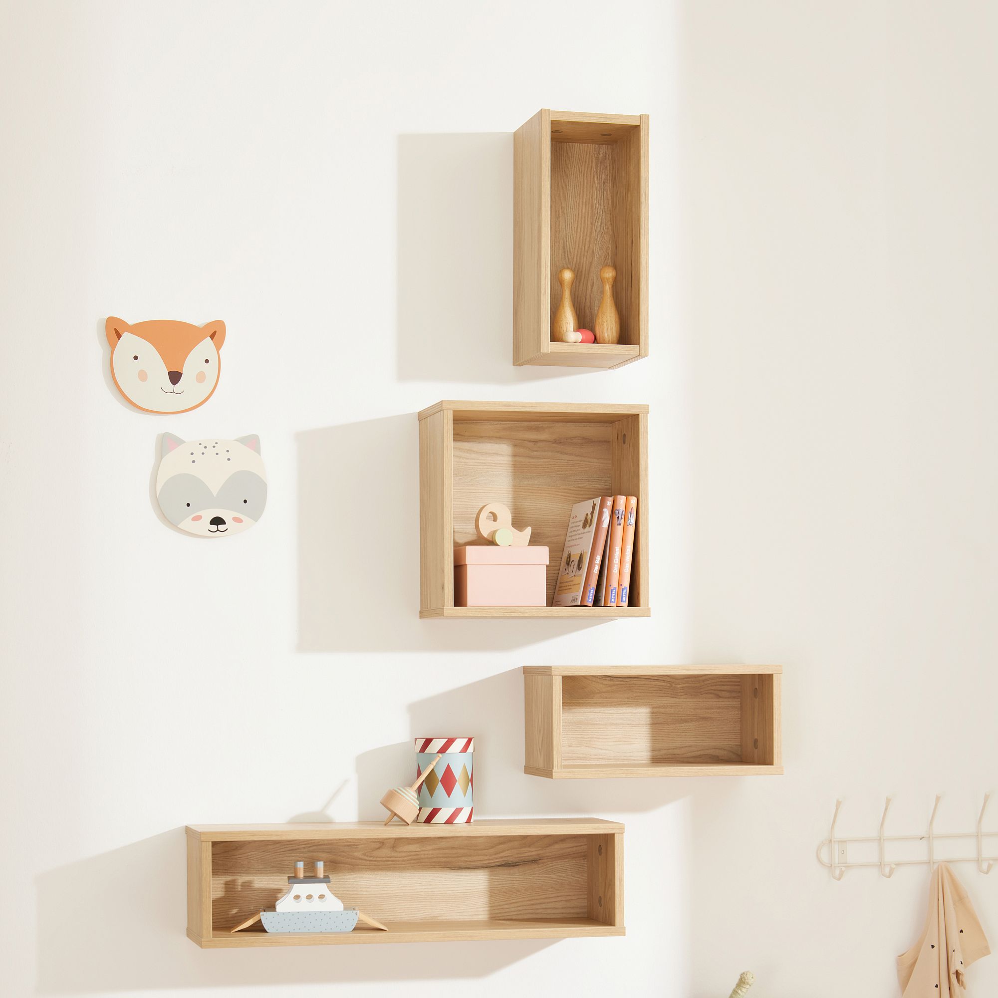 Wandregale aus Holz mit Spielzeug, Büchern und Wanddekorationen mit Tiergesichtern.