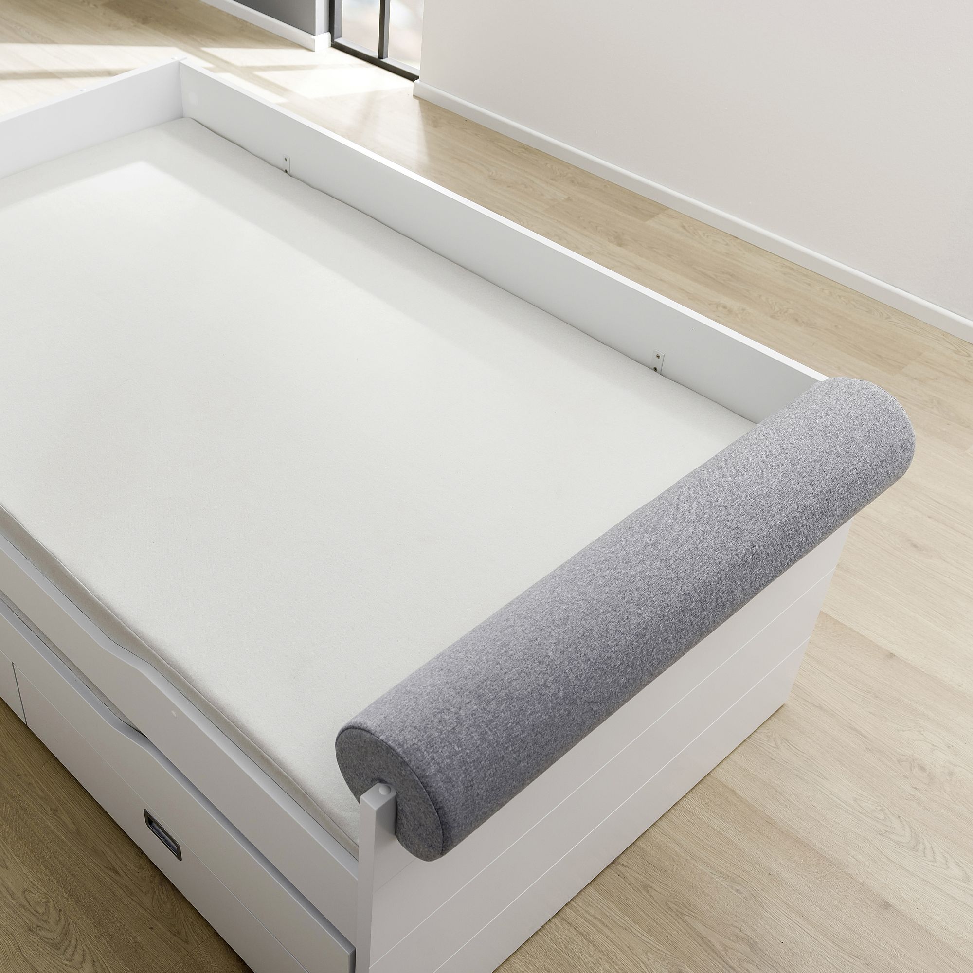 Comfort-Rolle 115 x Ø 20 cm, Mikrofaser Steingrau Weißes Daybed mit Schubladen und einem grauen zylindrischen Kissen am Kopfende.