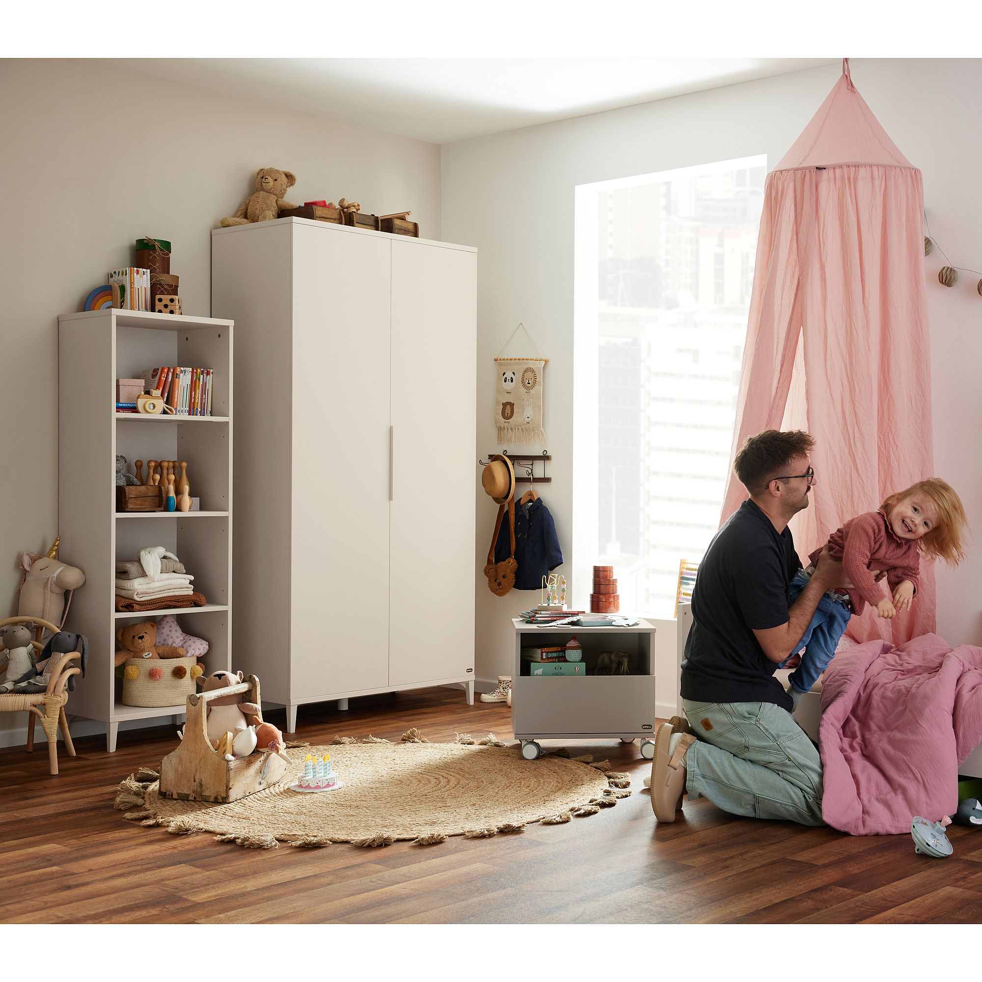 Der Vater spielt mit seiner Tochter in einem gemütlichen, gut eingerichteten Kinderzimmer mit Spielzeug und Büchern.