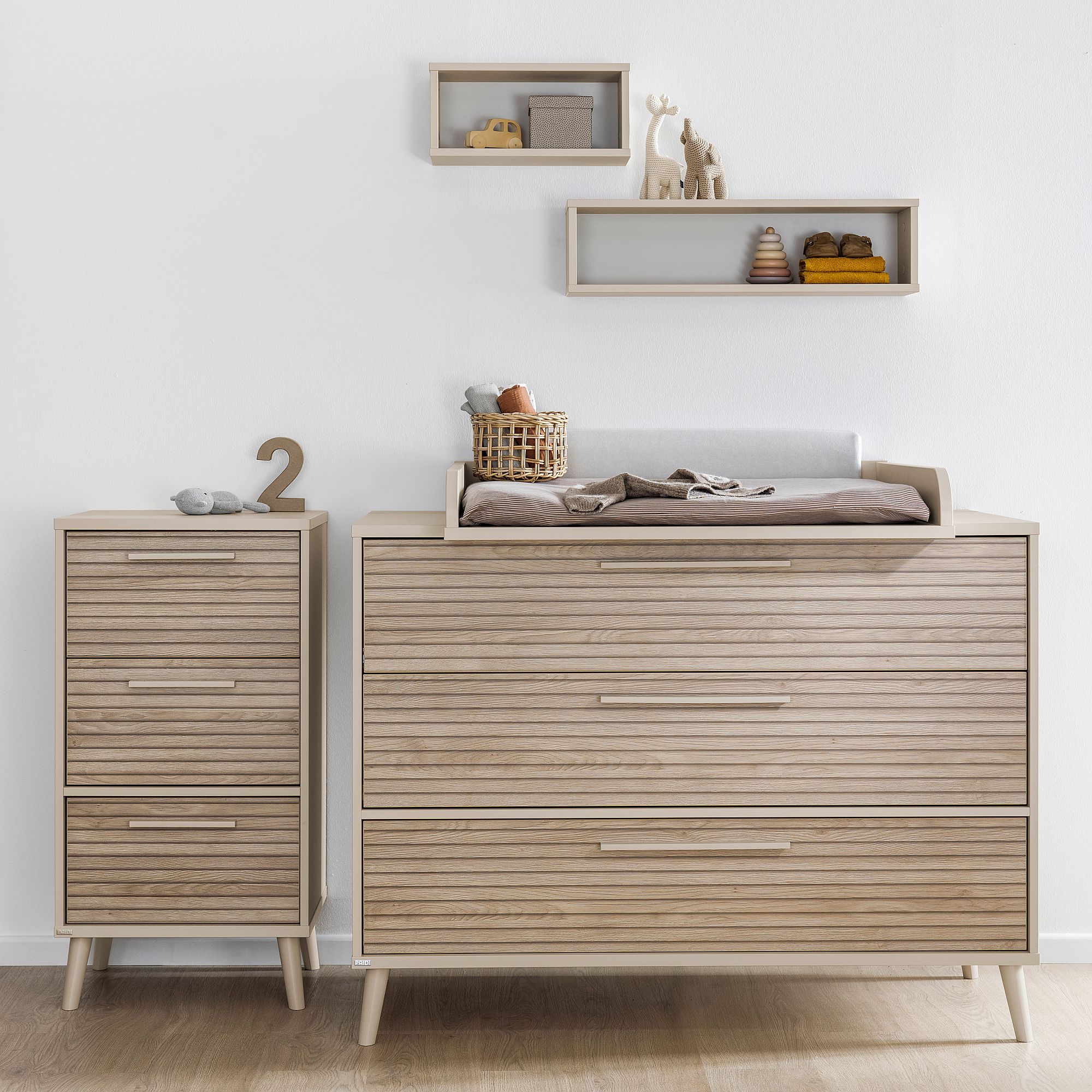 Wickeltisch und Kommode aus hellem Holz mit Spielzeug und Dekoration in den Regalen darüber.