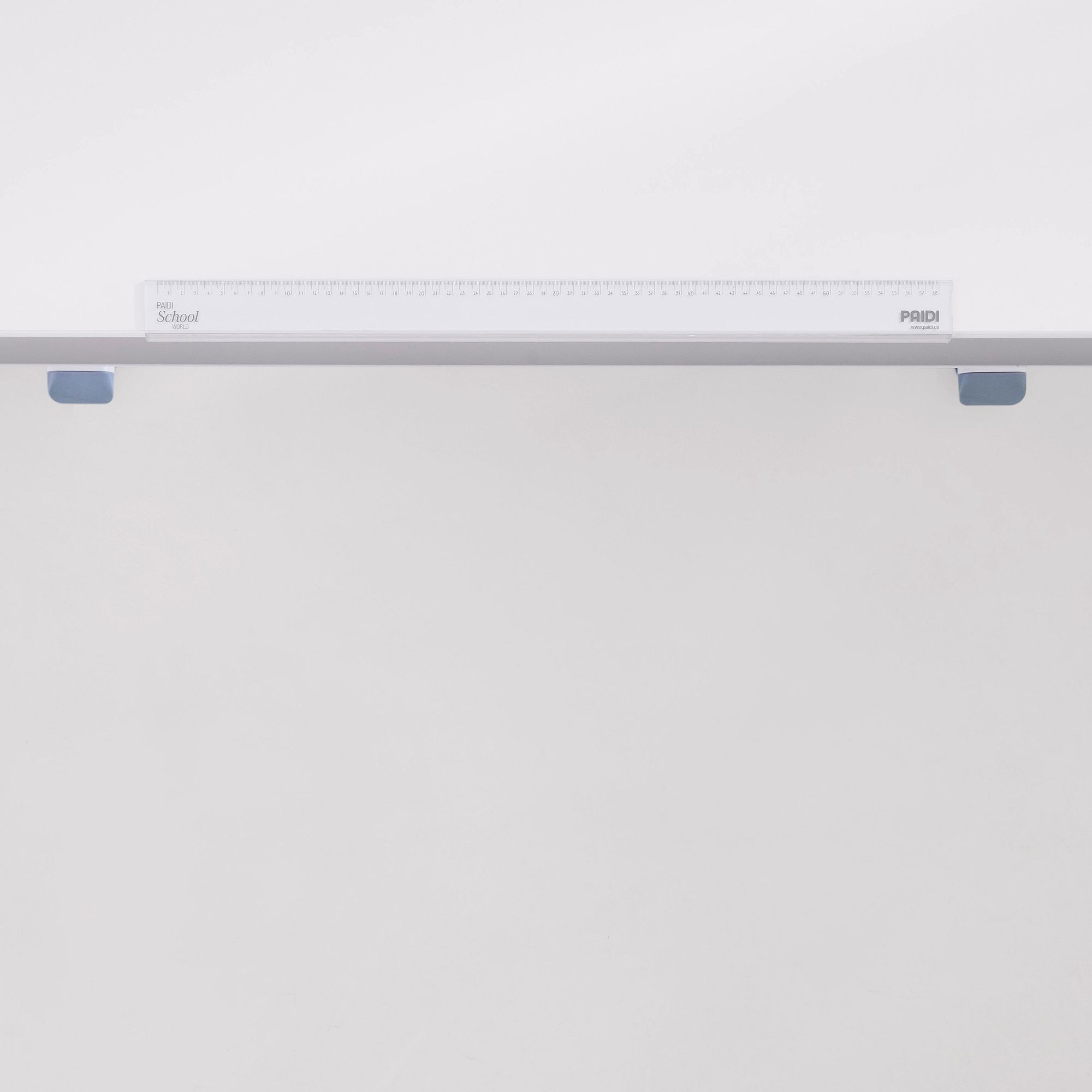 Ein durchsichtiges Plastiklineal auf einer weißen Oberfläche mit zwei blauen Clips.