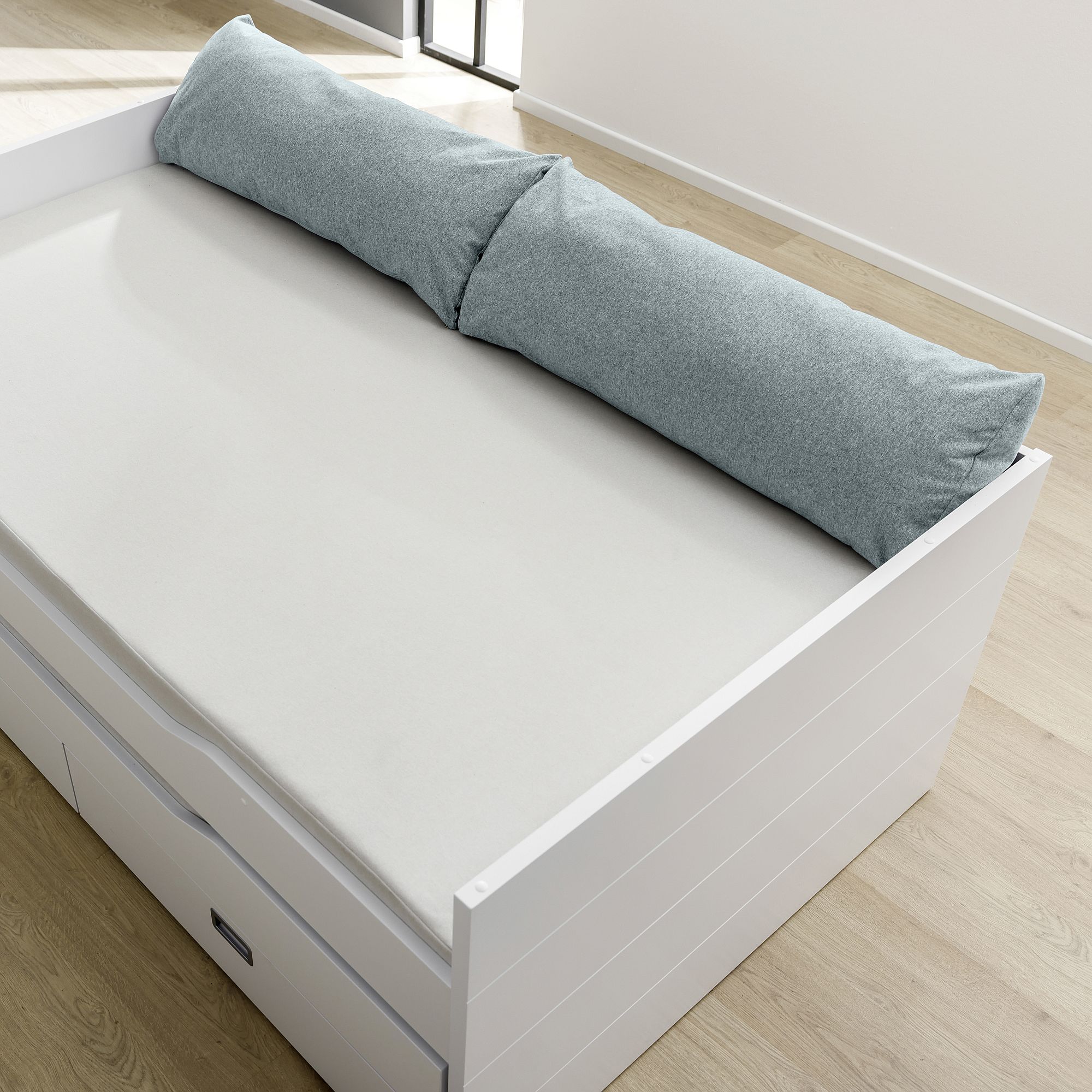 Ein weißes Daybed mit einem langen grauen Kissen und Schubladen darunter.