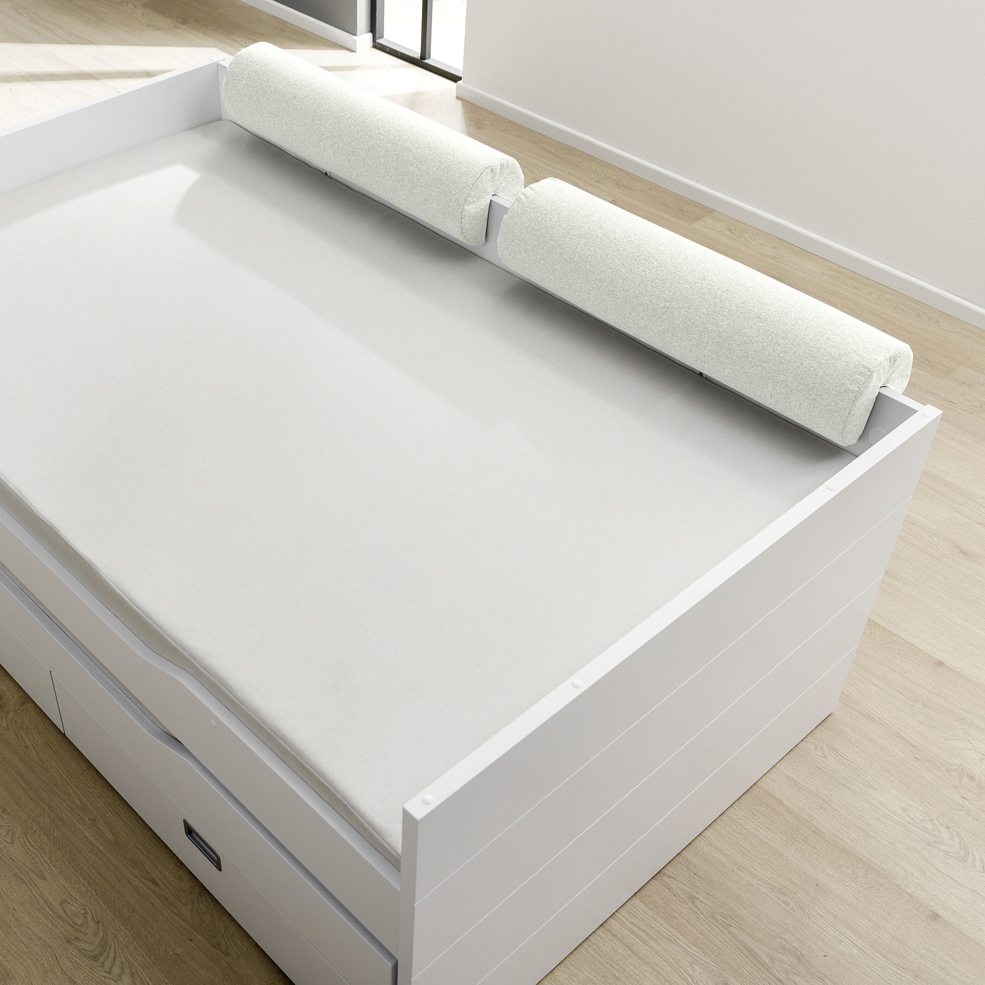 Comfort-Rolle 85,30 x Ø 20 cm, Mikrofaser Ivory Weißes Bett mit zwei zylindrischen Schaumstoffpolstern auf der Oberseite in einem hellen Raum.