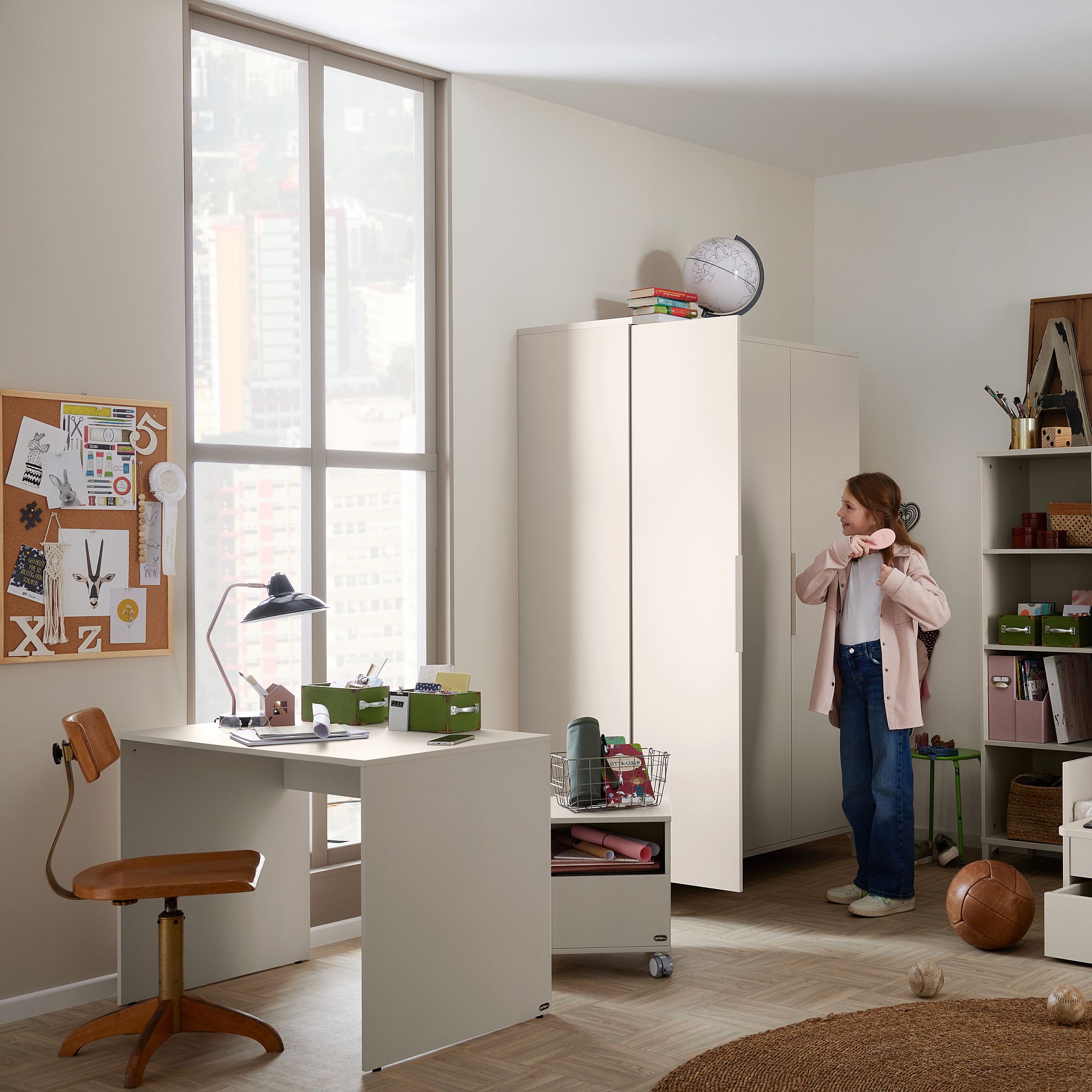 Ein Mädchen steht in einem modernen, organisierten Schlafzimmer mit Schreibtisch und Kleiderschrank.