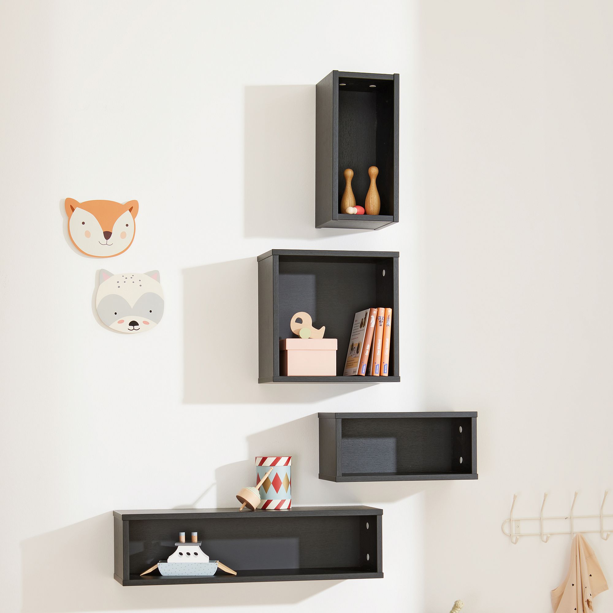Schwarze Wandregale mit Dekorationsartikeln, neben Fuchs und Waschbärgesicht Wandkunst.