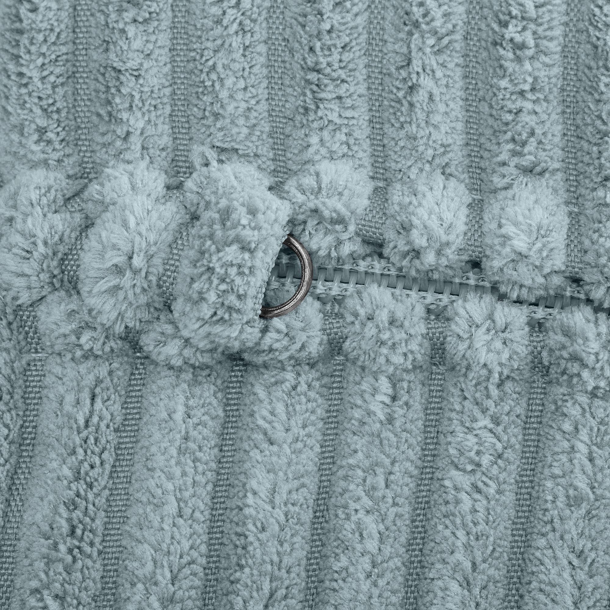 Nahaufnahme eines flauschigen, strukturierten Stoffes mit einem teilweise offenen Reißverschluss.