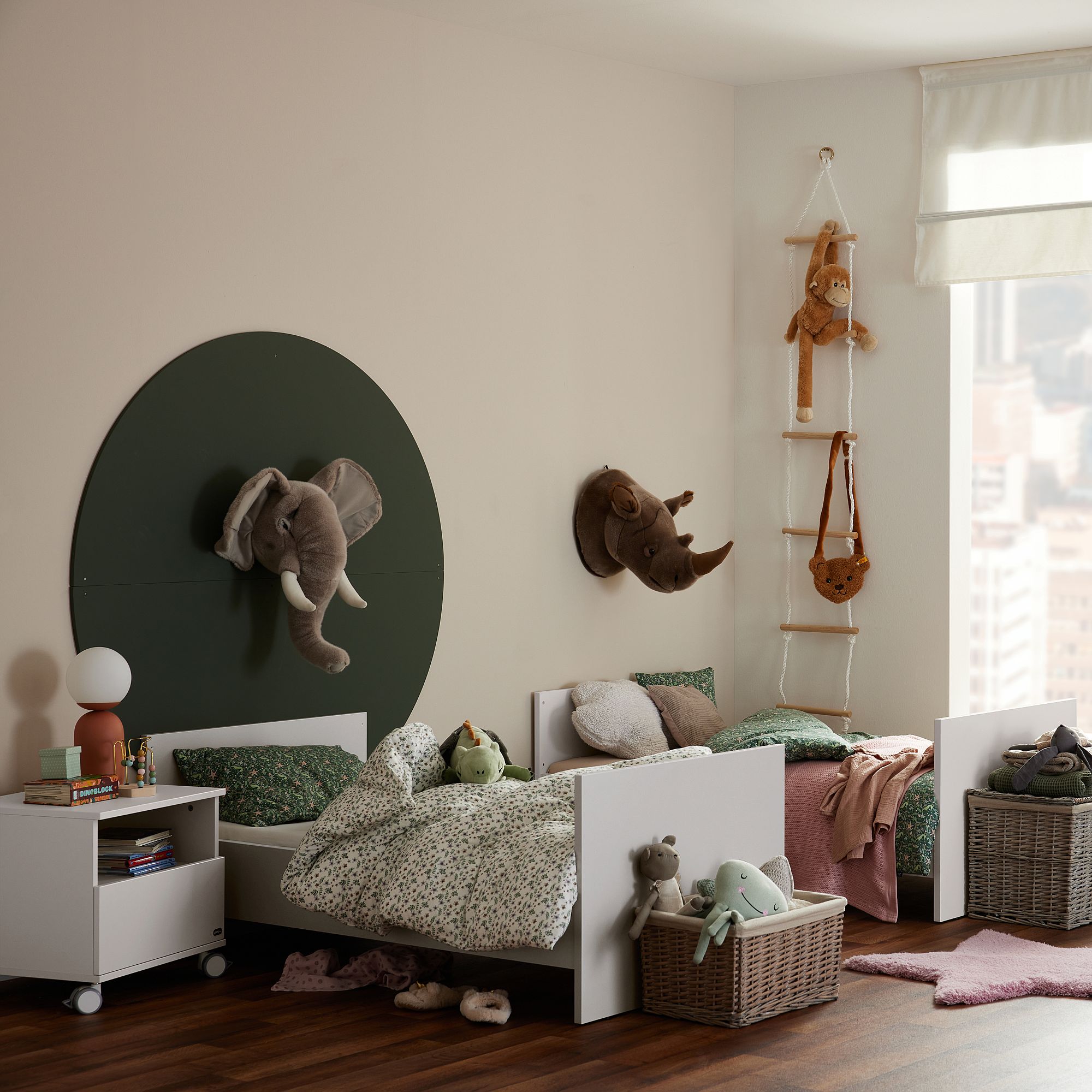 Zwei Kinderbetten mit Tierdekoration und Spielzeug in einem gemütlichen, lichtdurchfluteten Schlafzimmer.