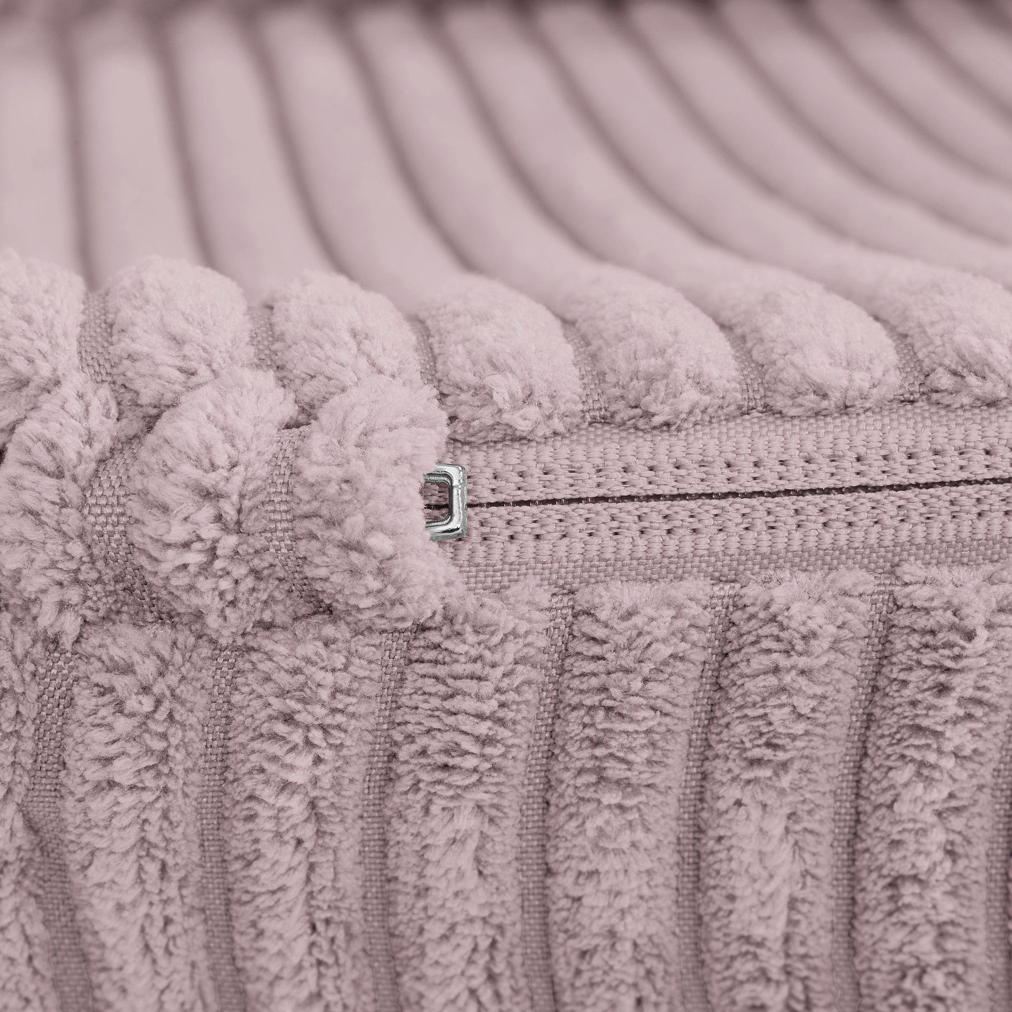 Nahaufnahme eines rosa gerippten Stoffes mit sichtbarem Reißverschluss.