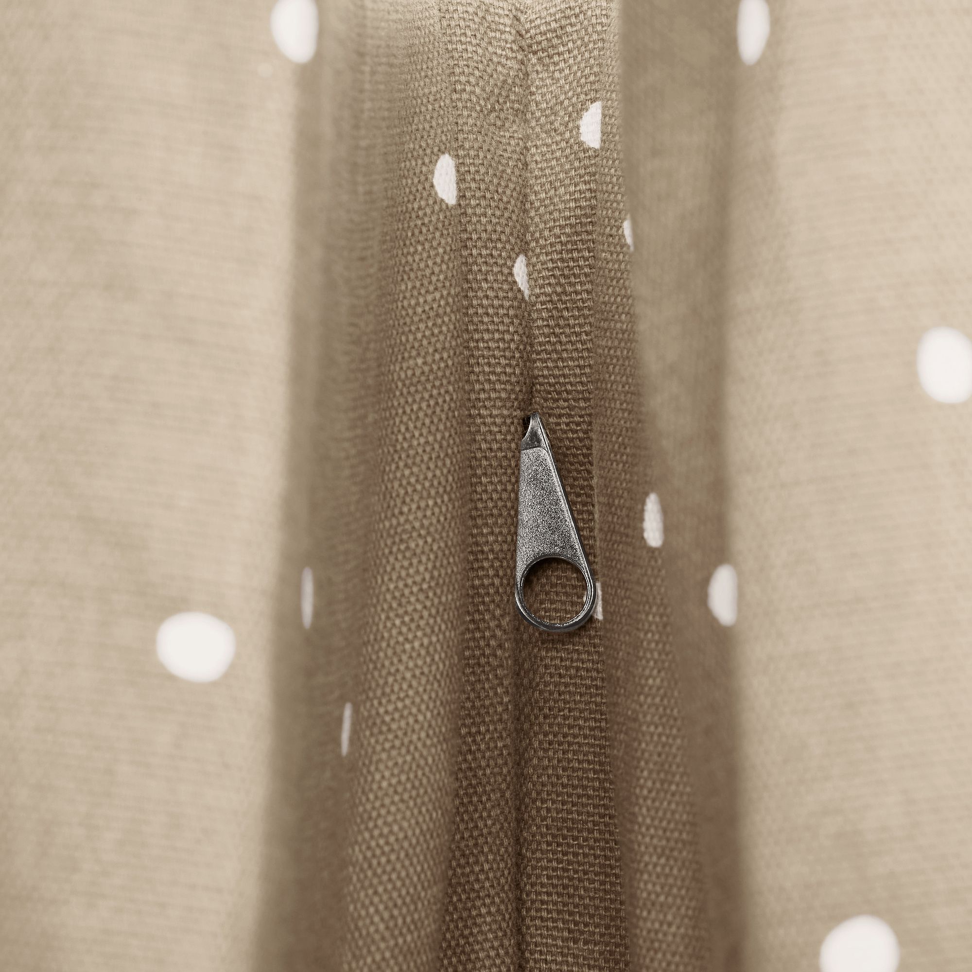 Nahaufnahme eines braunen gepunkteten Stoffes mit einem Reißverschluss in der Mitte.