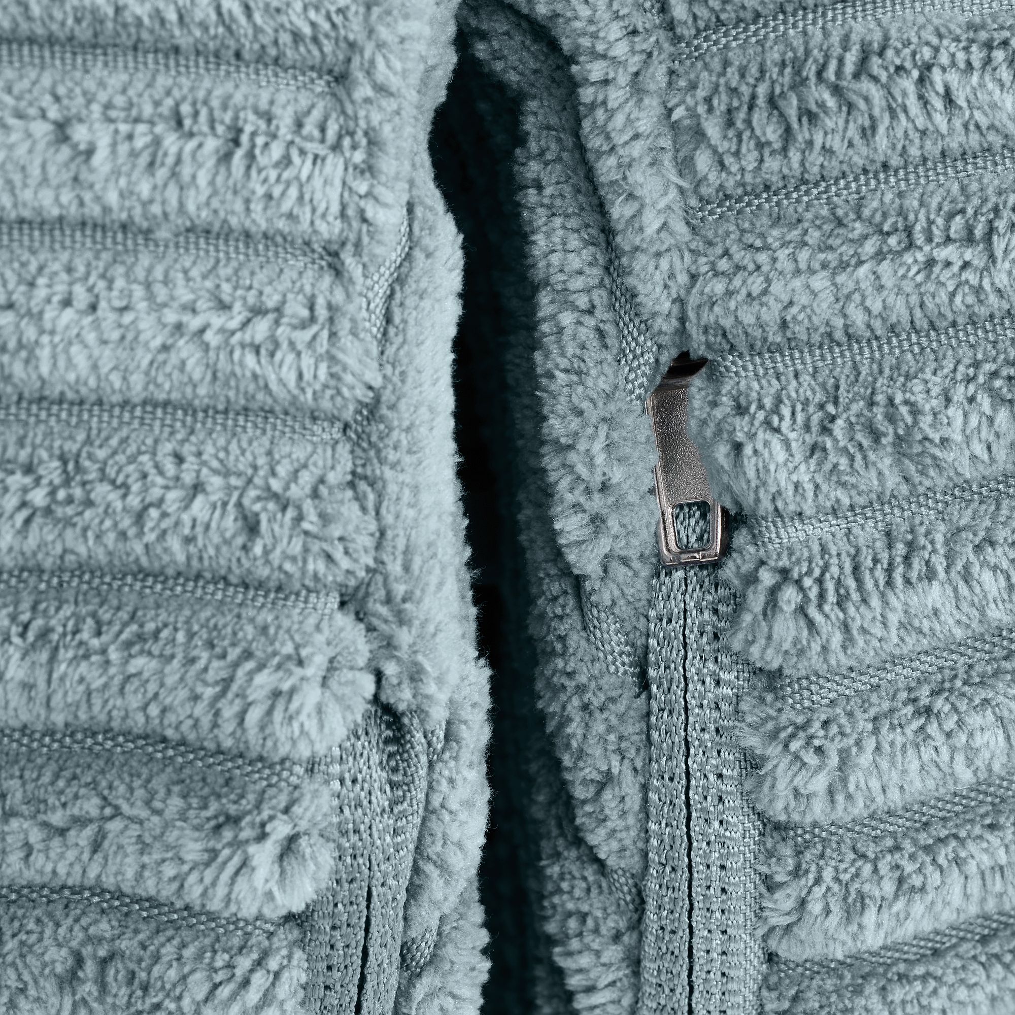 Nahaufnahme eines silbernen Reißverschlusses auf einem weichen, strukturierten, hellblauen Stoff.