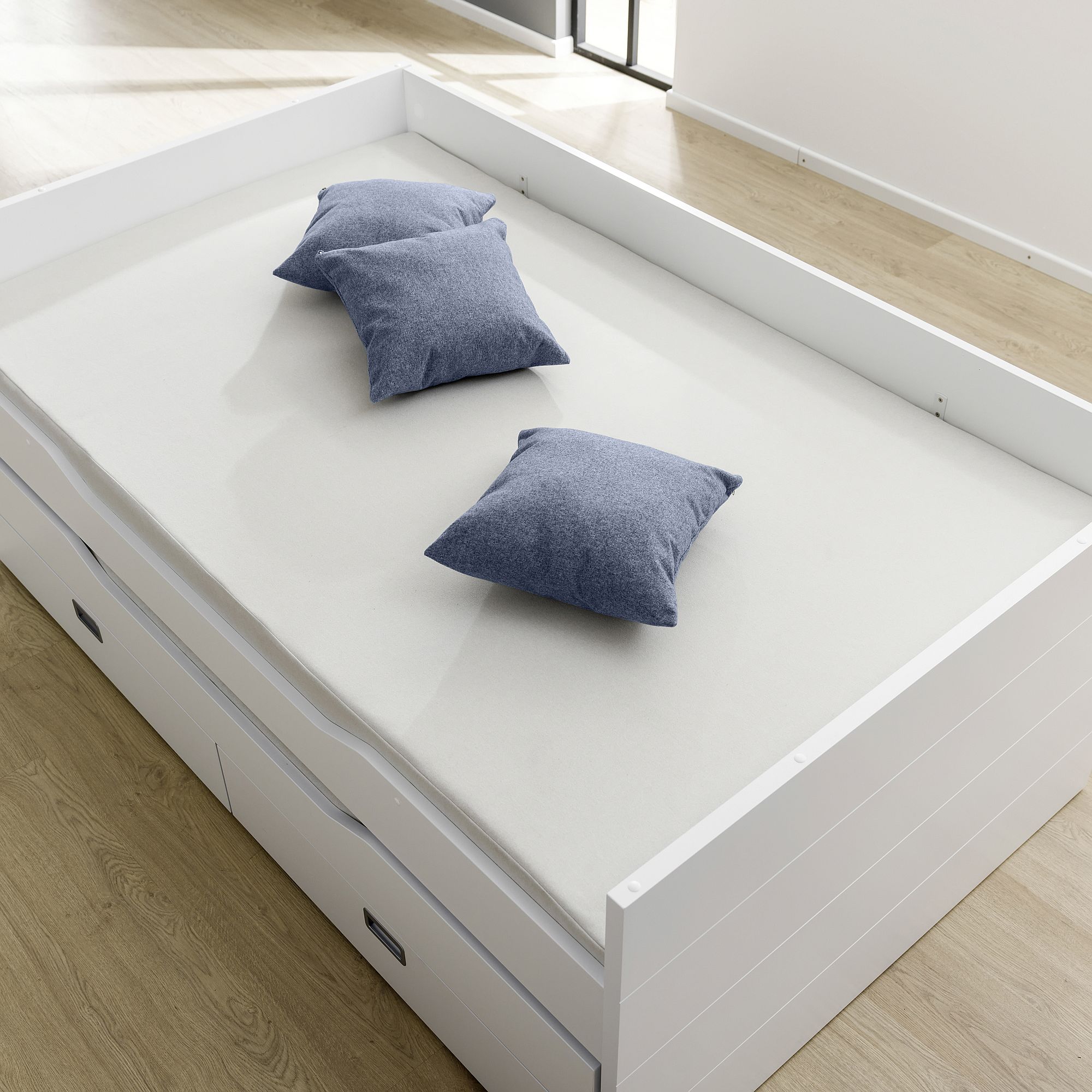 Partykissen 40 x 40 cm, Mikrofaser Tintenblau Weißes Bett mit drei blauen Kissen auf einer hellen Matratze in einem hellen Raum.