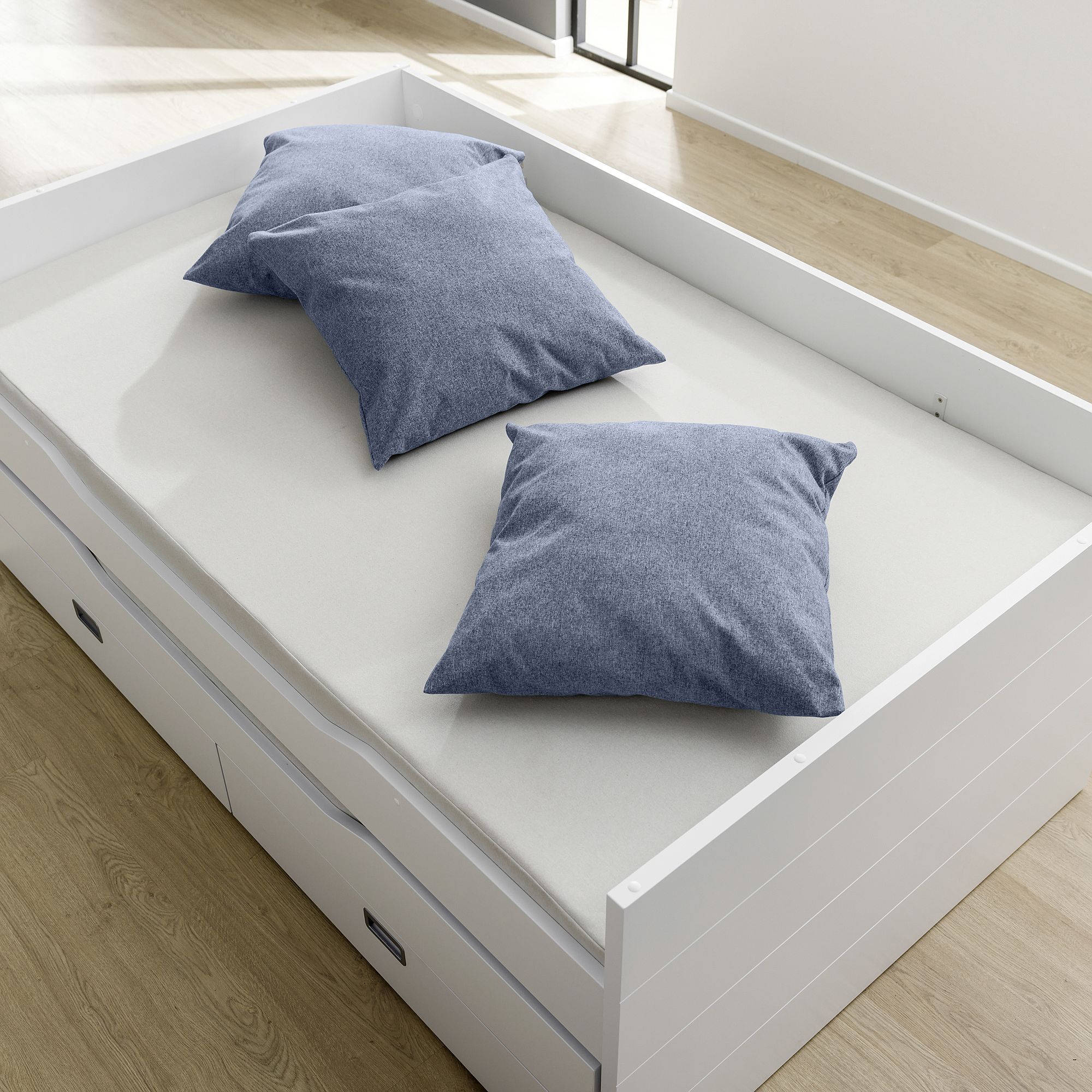 Partykissen 60 x 60 cm, Mikrofaser Tintenblau Weißes Daybed mit zwei blauen Kissen auf hellem Holzboden in einem hellen Raum.