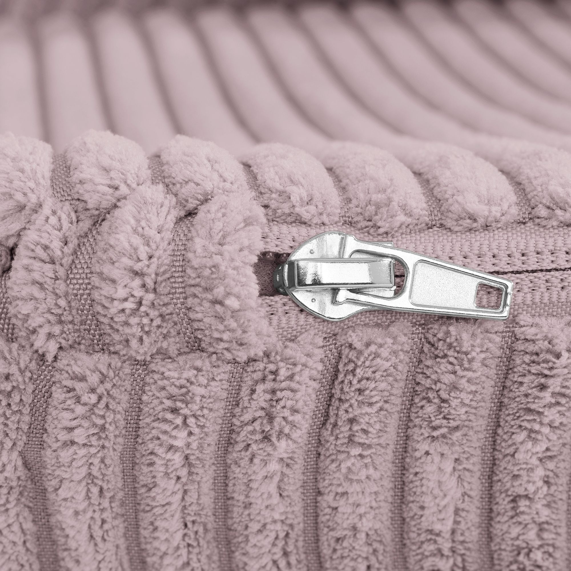 Nahaufnahme eines silbernen Reißverschlusses auf weichem, geripptem, hellviolettem Stoff.